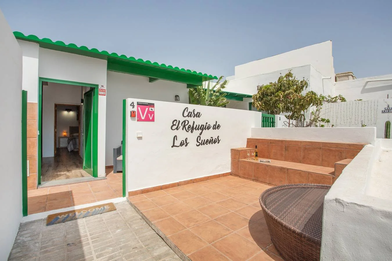 Fachada blanca con carpintería verde y patio